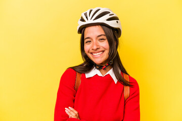 Young student hispanic woman wearing a bike helmet isolated on yellow background laughing and having fun.