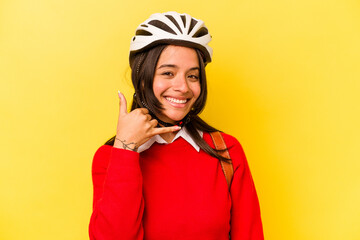 Young student hispanic woman wearing a bike helmet isolated on yellow background showing a mobile phone call gesture with fingers.