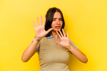 Young hispanic woman isolated on yellow background being shocked due to an imminent danger