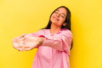 Young hispanic woman isolated on yellow background stretching arms, relaxed position.