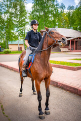 Obraz premium Lovely young woman wearing helmet riding her brown horse