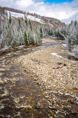 The not frozen bed of a beautiful winding Chibit River flowing through a snow-covered valley...