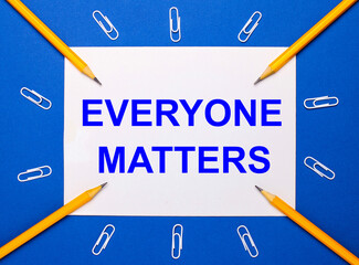 On a blue background, white paper clips, yellow pencils and a white sheet of paper with the text...