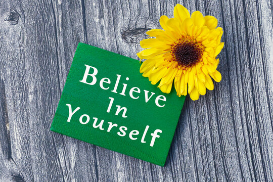 Believe in yourself word on green wooden cube with and sunflower.