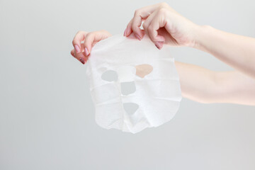 fabric cosmetic mask in the hands on a white background. beauty treatments. cosmetics for women