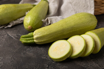 Fresh organic zucchini whole and slices on a black wooden table.Vegan food.Healthy vegan food. Fresh organic product.Vegetables. Healthy food.Copy space.