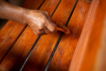 Close-up photo of a man's hand holding a oil-painted plot of a wooden chair