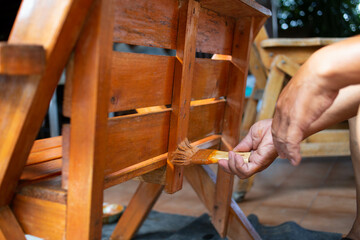 Close-up photo of a man's hand holding a oil-painted plot of a wooden chair