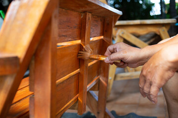Close-up photo of a man's hand holding a oil-painted plot of a wooden chair