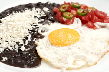 Fried egg accompanied with tomato and sliced jalapeño pepper, beans with grated cheese