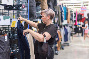 Real woman with short hair and glasses checks out some pants in a sportswear store.