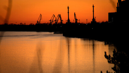 Sunset on the Volga river. Silhouettes of port cranes on the river bank. Views Of the river port of...