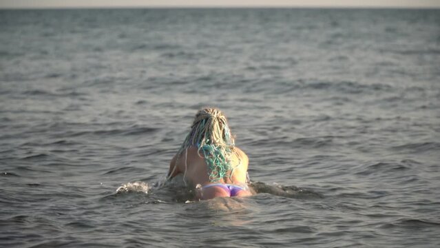 Young sexy woman in bikini dives into the sea. Hot beautiful woman swims in the water