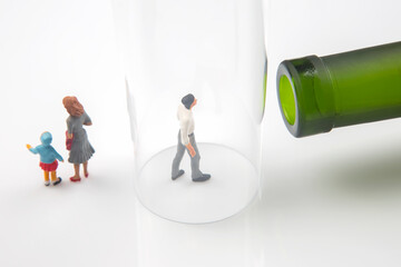 miniature people. man addicted to alcohol on the background of a bottle of wine and a glass and a...
