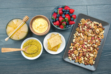 fresh assorted honey, nuts, strawberries and blueberries on a wooden background. healthy organic vitamin food.