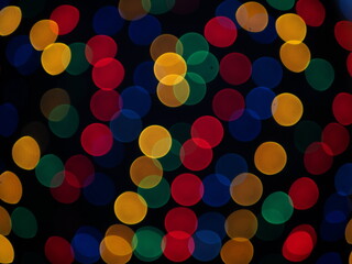 Colorful abstract background. Multicolored garland with bokeh effect on a black background.