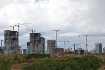 Tower crane on the construction of a building with a frame of reinforced concrete. Sunlit against a blue sky.