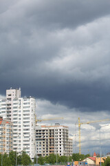 Fototapeta premium Tower crane on the construction of a building with a frame of reinforced concrete. Sunlit against a blue sky.