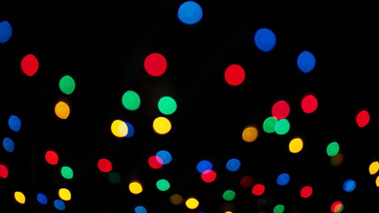 Colorful abstract background. Multicolored garland with bokeh effect on a black background.