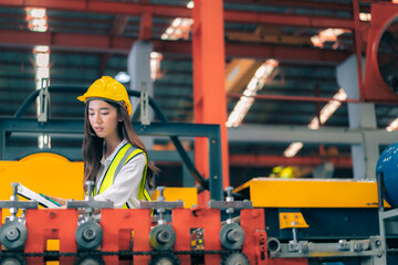 Obraz na płótnie Canvas Happy professional beautiful Asian woman industrial engineer/worker/technician with safety hardhat use clipboard to inspect quality control of machinery in production steel manufacture factory plant