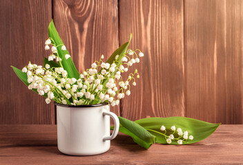Bouquet of white lilies of the valley on a brown wooden background.