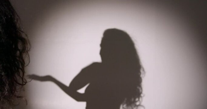 Female silhouette dancing in shadow in studio
