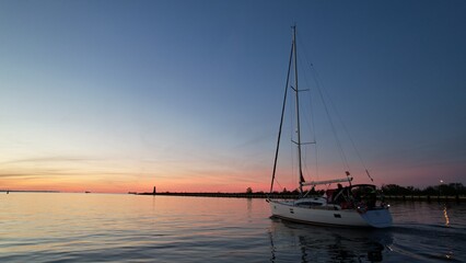 Sailing yacht on the background of the fiery sunset of the Baltic Sea.