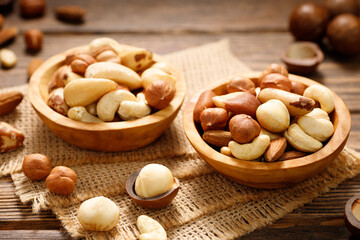 Various nuts in bowl - cashew, hazelnuts, almonds, brazilian nuts and macadamia on a wooden table....