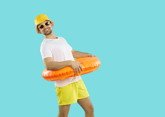 Funny young man in sun hat and sunglasses with lifebuoy excited about summertime vacations. Smiling teen guy ready for great summer holidays or adventures. Tourism and travel concept.