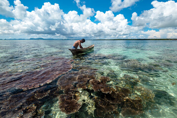 Bajau laut with his boat with clear coral reef in Semporna Sabah Borneo Malaysia