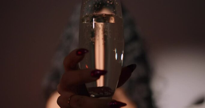 Defocused curly haired woman with champagne glass closeup