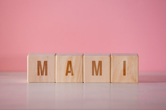 Four wooden cubes with the written word "mami" on pink background