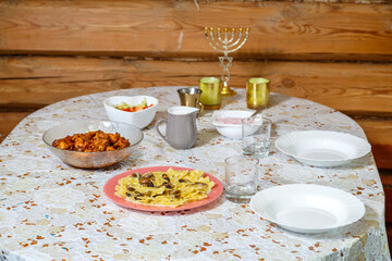 A festively laid Shabbat table with candles and a menorah.