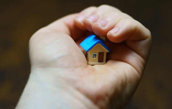Small toy house in the male palm. Real estate concept.