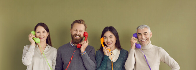 Group of happy people talking on colorful landline phones. Studio portrait of four smiling males...