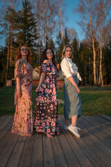 Naklejka premium Three girls girlfriends pose at the forest recreation center.