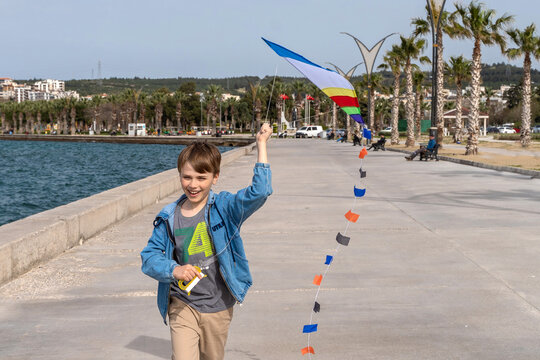 Child runs along sea embankment and  kite skiing. Positive leisure concept. Childhood.