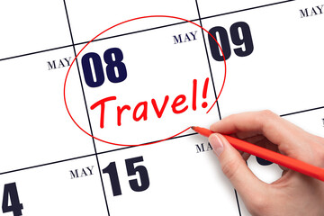 Hand drawing a red circle and writing the text TRAVEL on the calendar date 8 May. Travel planning.