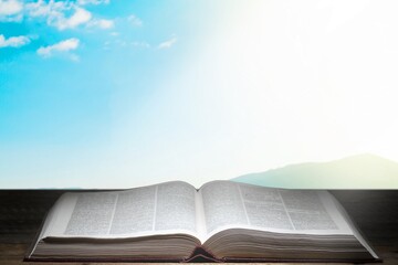 An open antique book on wooden table with vintage key