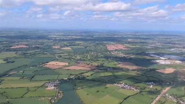 Flying over east ireland overlooking the irish green fields and scattered houses and cottages under a blue cloudy sky