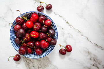 Fresh sweet cherries bowl on marble background. Top view with copy space - Powered by Adobe