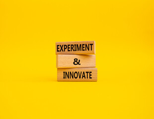 Experiment and innovate symbol. Concept words Experiment and innovate on wooden blocks. Beautiful yellow background. Business and Experiment and innovate concept. Copy space.