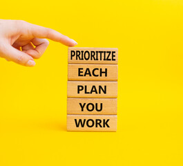 Priority, plan and work symbol. Wooden blocks with words Prioritize each plan you work. Beautiful yellow background. Businessman hand. Business and Prioritize each plan you work concept. Copy space