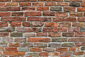 Wall of ancient red and grey bricks. Detail of the medieval brick wall of an old church in the...