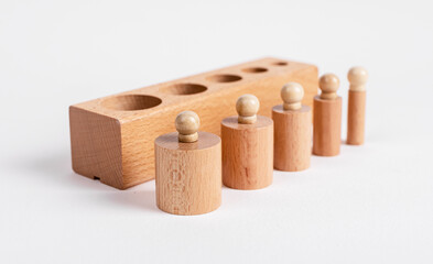 Block and Montessori knobbed cylinders placed in correct order from thicker to thinner. Wooden...