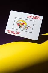 Joker card in flight on a yellow and black background.