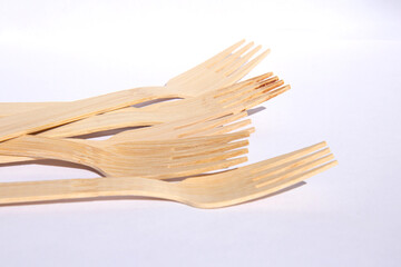 Wooden eco bamboo cutlery forks on bright white background. Meal time concept