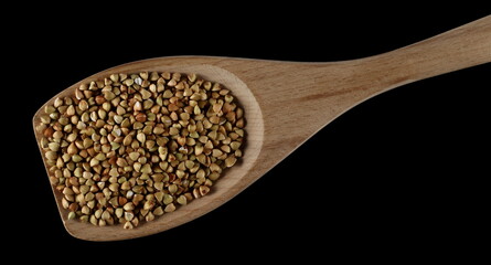 Buckwheat pile in wooden spoon isolated on black, top view 