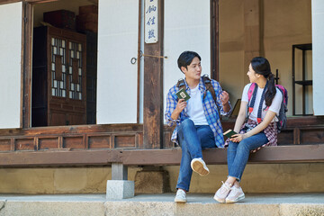 Naklejka na ściany i meble 한국의 옛날 전통 가옥 마루에 걸터 앉아서 서로 바라보며 즐겁게 대화 또는 설명하고있는 아시아 한국 남자 여자 모델