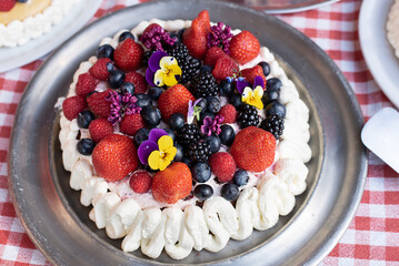 Dessert for the holiday, homemade cake with whipped cream, berries and edible flowers.